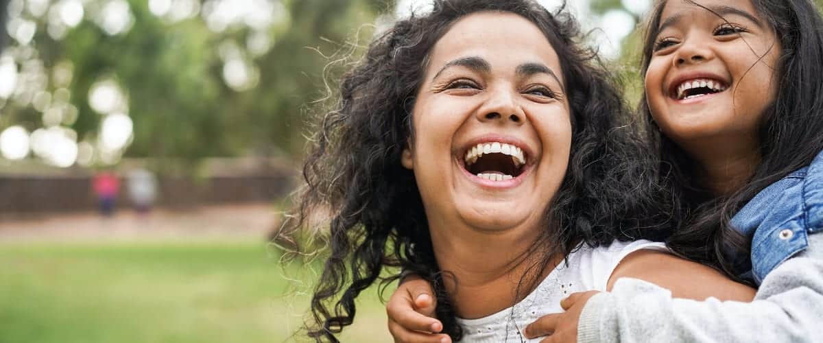 A Latina mother laughs with her young daughter