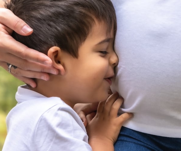 A young boy hugs his pregnant mom