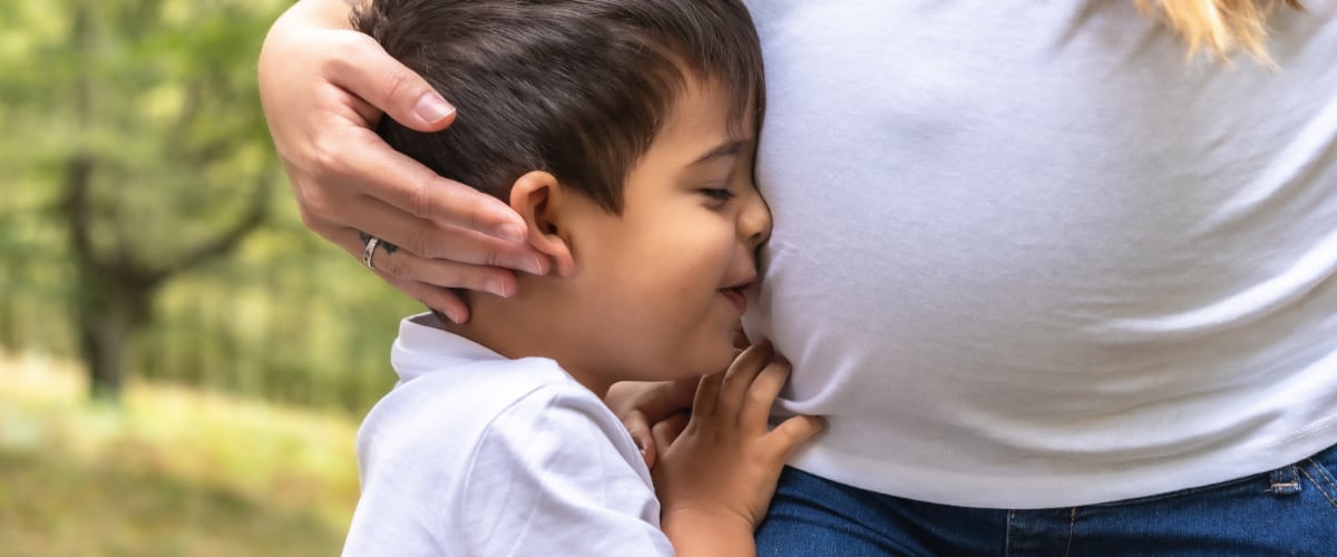 A young boy hugs his pregnant mom