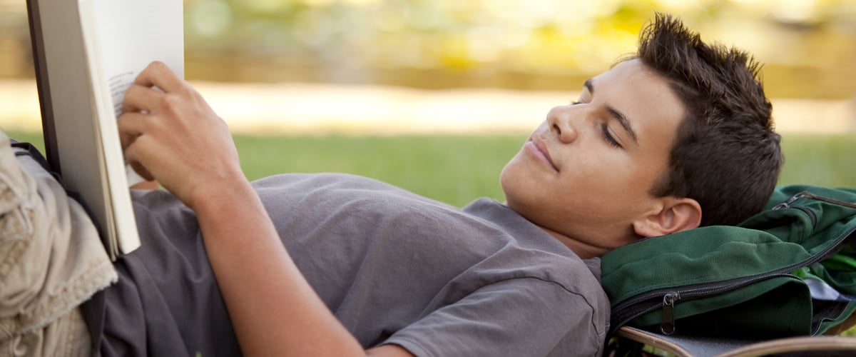 A teen boy reading a book