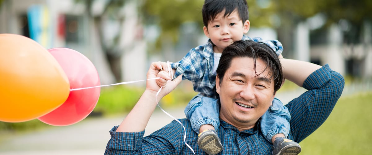 A Chinese father holds his son on his shoulders